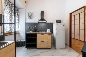 A modern kitchen with a built-in stove, microwave, and refrigerator. There is a window with decorative ironwork and a sliding door with a traditional design. - Gianicolense Apartment (Rome)