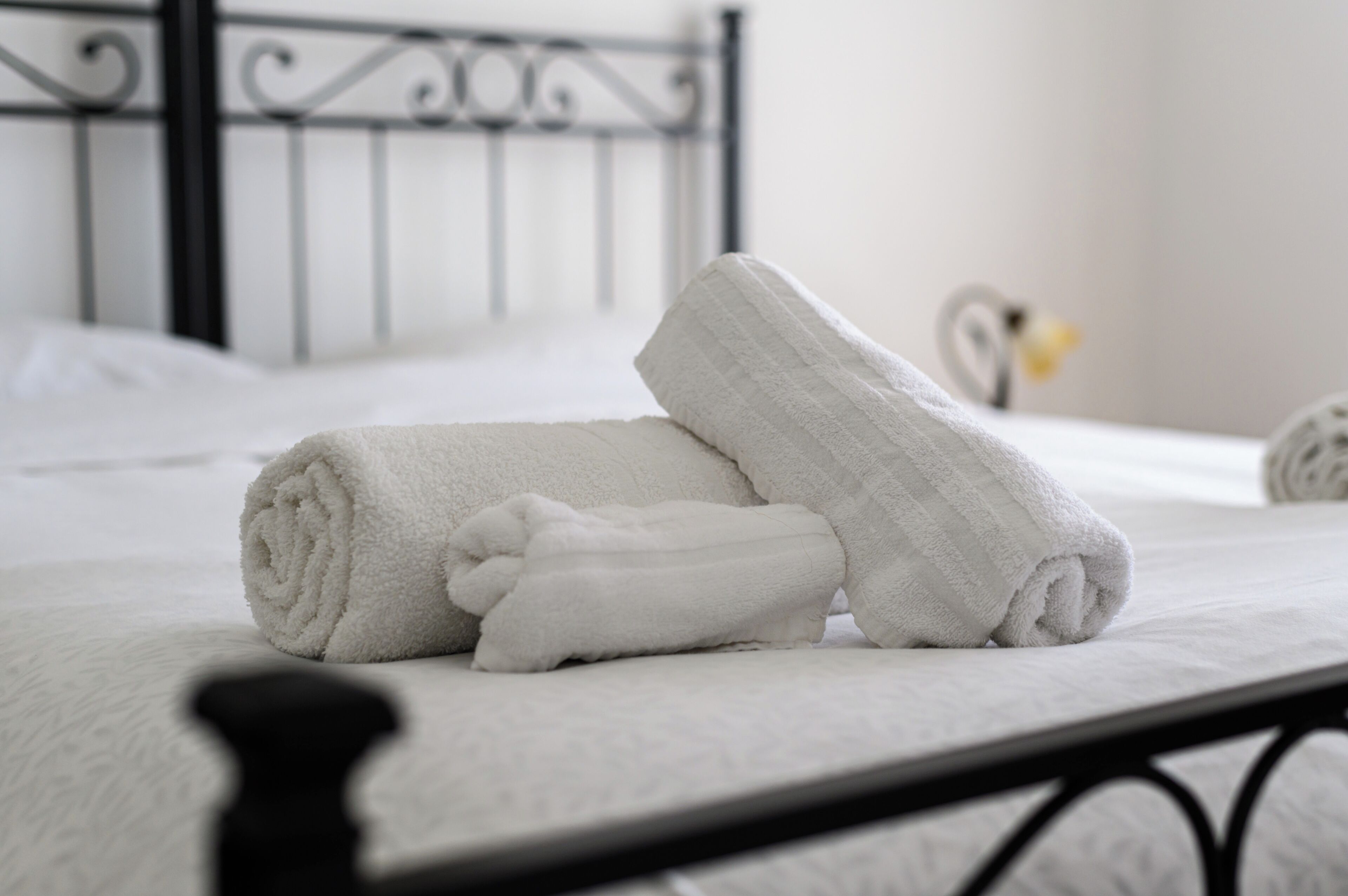 A neatly made bed with white linens and a rolled towel.