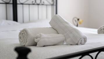A neatly made bed with white linens and a rolled towel.