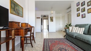 A living room with a sofa, a coffee table, a TV, and a wooden desk with chairs. - Via Coriolano 8 (Naples)