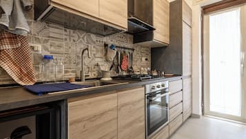 Una cocina moderna con armarios de madera, horno empotrado y un amplio ventanal.