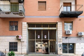 Ein Gebäude mit einem befahrbaren Eingang, Klimaanlagen und einem sichtbaren Balkon.