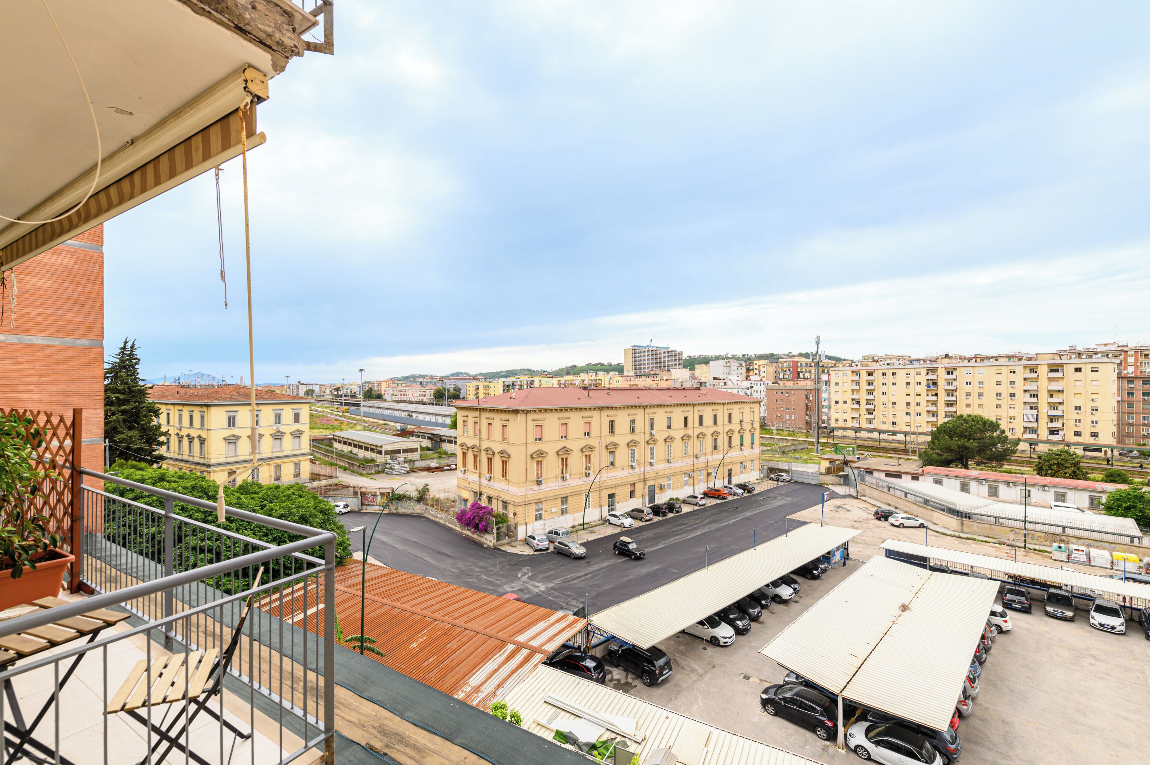 Un balcon donnant sur un parking et des immeubles.