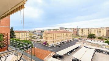 Un balcon donnant sur un parking et des immeubles.