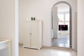 Un armari blanc amb mirall, un terra de rajoles i una porta que condueix a una altra habitació.