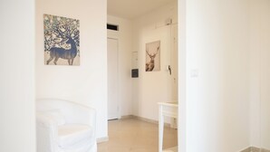 Un interno bianco con una sedia bianca, un tavolino e due quadri raffiguranti cervi alle pareti.
