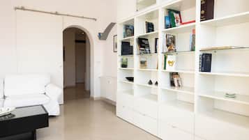 Ein modernes Wohnzimmer mit einem weißen Sofa, einem schwarzen Couchtisch und einem weißen Bücherregal, das mit Büchern und Dekoration gefüllt ist.