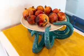 A plate of pomegranates on a ceramic stand with a yellow cloth underneath. - Purgatorio Terrace (Naples)