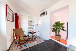 A modern living room with a sofa, a small table, a bookshelf, and a potted plant. - Purgatorio Terrace (Naples)