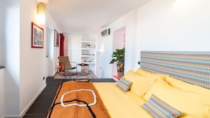 Ein modernes Hotelzimmer mit einem großen Bett, einem kleinen Schreibtisch, einem Stuhl und einer Zimmerpflanze.