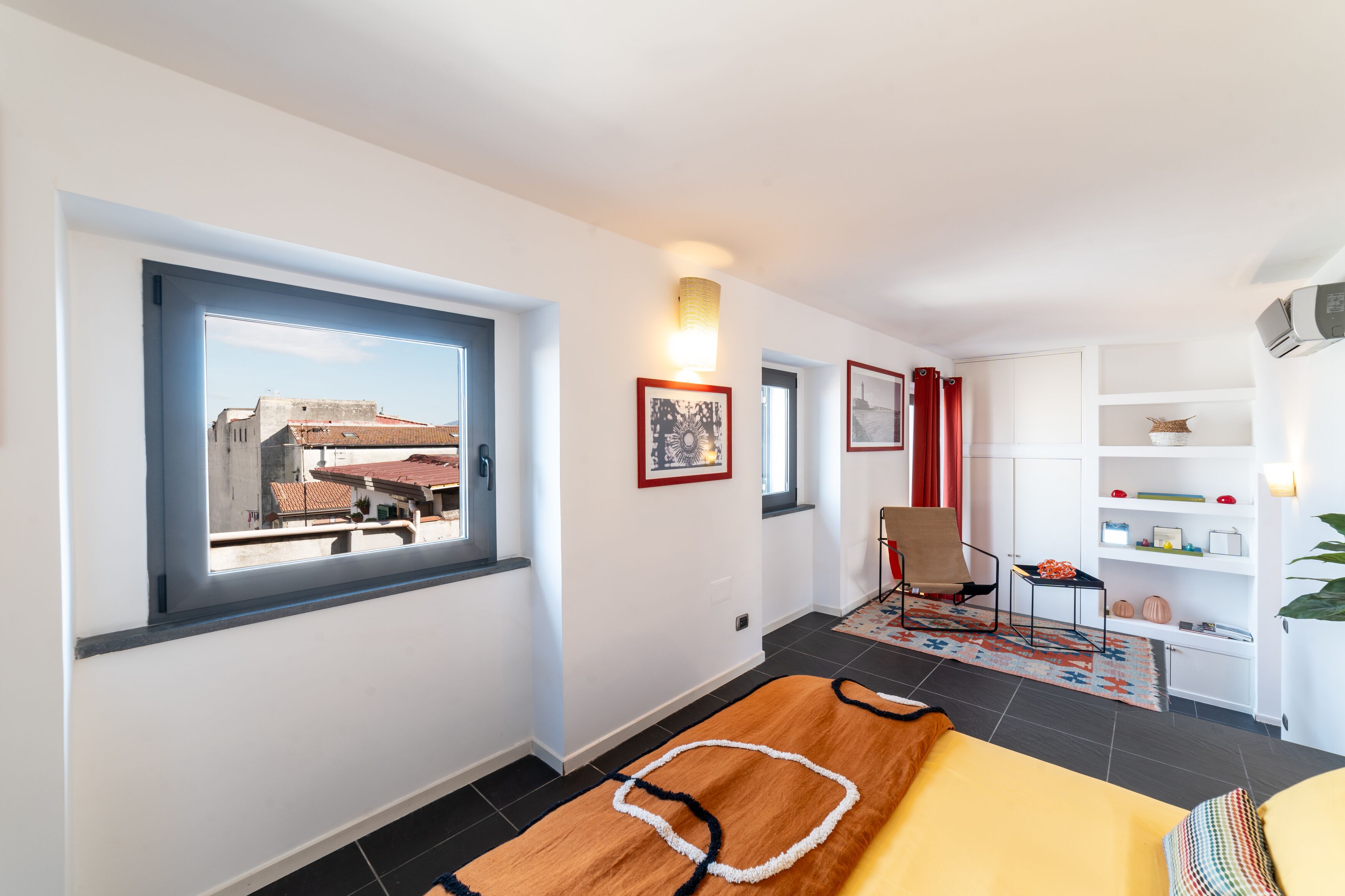 Une chambre moderne avec une grande fenêtre, un lit, une chaise et une petite table.