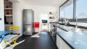 Eine moderne Küche mit einem Edelstahl-Kühlschrank, einem roten Stuhl und einem blauen Tisch.