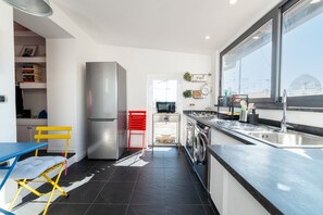 Eine moderne Küche mit einem Edelstahl-Kühlschrank, einem roten Stuhl und einem blauen Tisch.