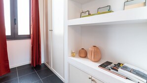Ein Zimmer mit einem weißen Schrank, einem Fenster mit roten Vorhängen und einem Fliesenboden.