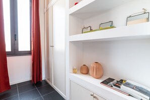 Ein Zimmer mit einem weißen Schrank, einem Fenster mit roten Vorhängen und einem Fliesenboden.