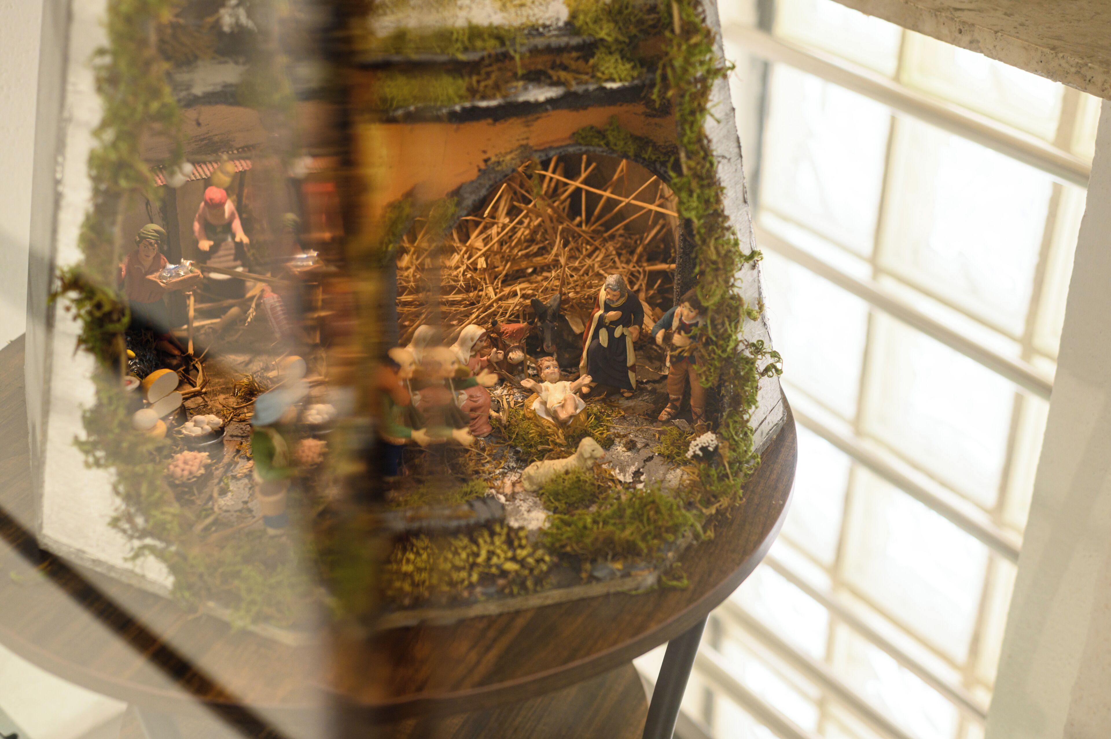 Modelo de una escena rústica con figuras en miniatura y una estructura de rueda, todo dentro de una vitrina de cristal.