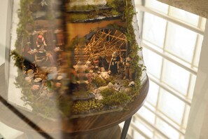 A model of a rustic scene with miniature figures and a wheel structure, set in a glass enclosure. - A Tazzulella - Vico Graziella 12 (Naples)