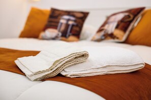 A neatly made bed with white linens and two pillows with a coffee theme. - A Tazzulella - Vico Graziella 12 (Naples)