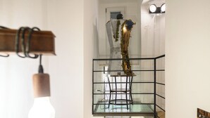 Interior moderno com guarda-corpo de vidro, luminária pendente e planta decorativa.