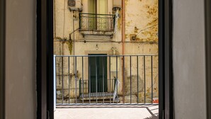 Visão através de um portão de metal de um edifício com varanda, porta e janela.