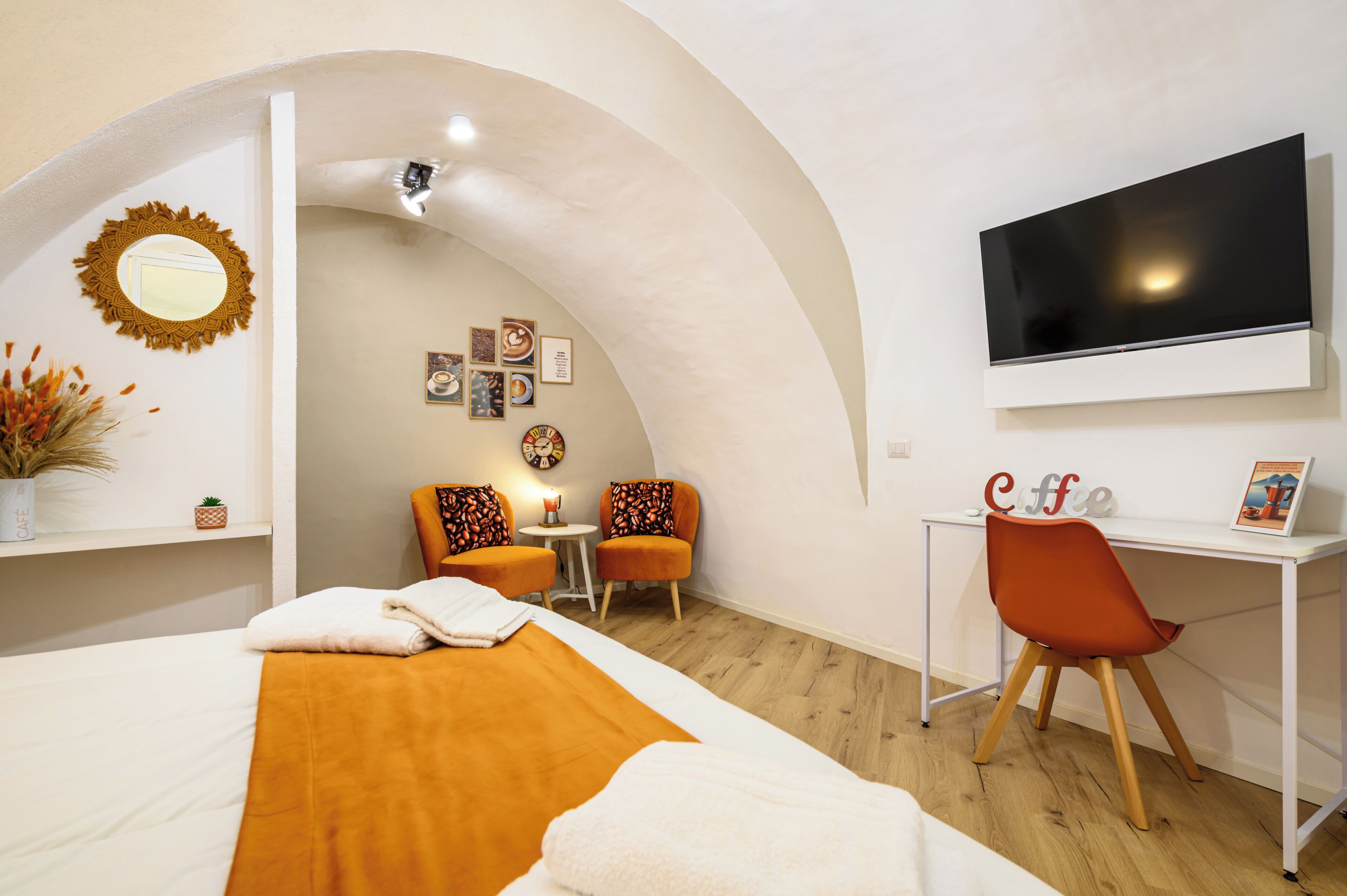 A hotel room with a bed, a desk, a TV, and a small table with chairs.