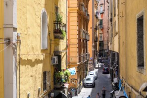 A narrow street with yellow buildings, parked cars, and visible balconies. - A Tazzulella - Vico Graziella 12 (Naples)