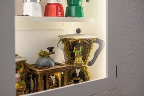 A shelf with various kitchen appliances and a decorative coffee pot. - A Tazzulella - Vico Graziella 12 (Naples)