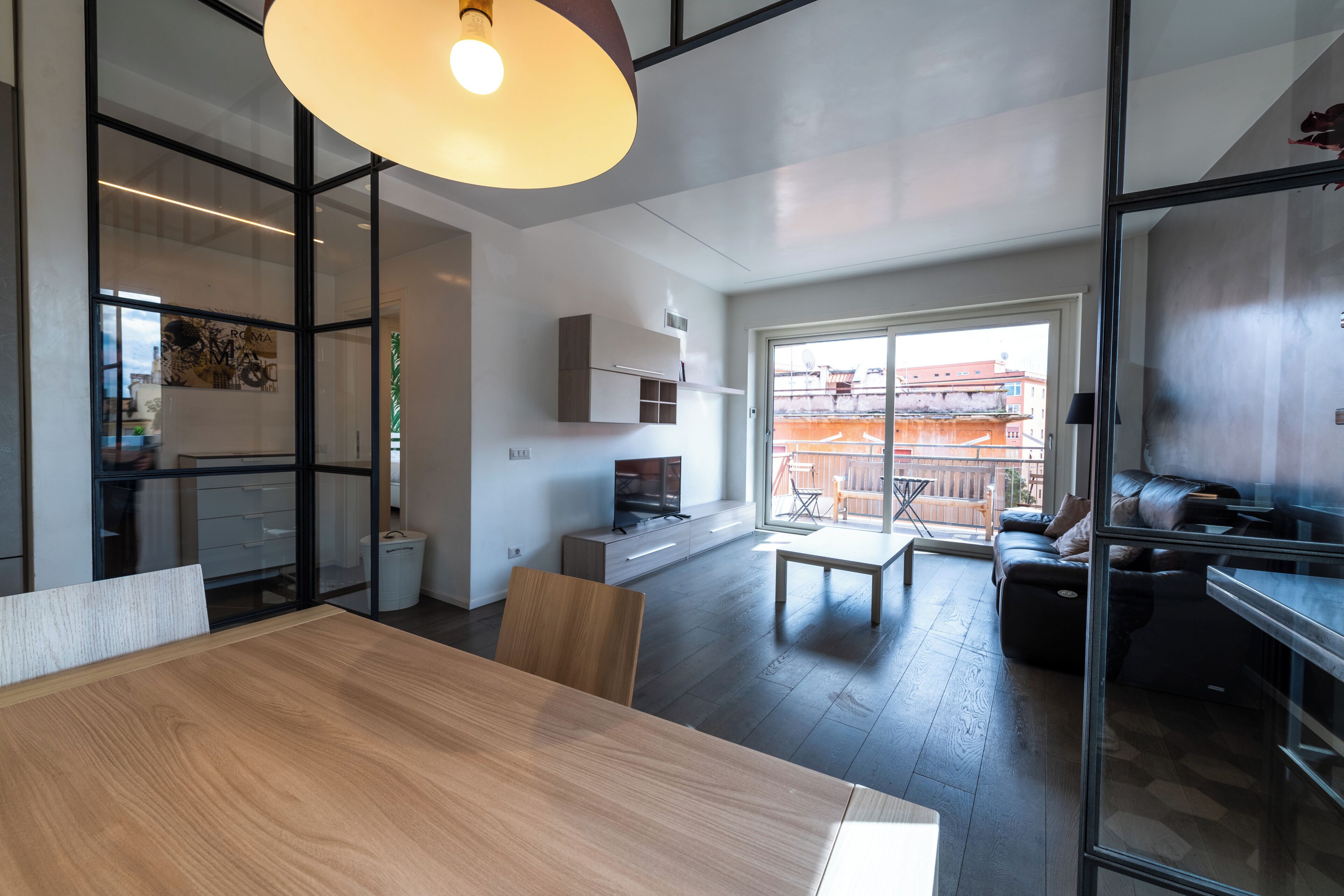 A modern living space with a dining area, kitchen, and a balcony with a view.