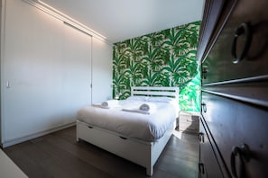 A bedroom with a white bed, a white headboard, and a green leaf-patterned wall. - Time 4 Rome (Rome)