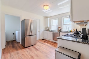 A modern kitchen with stainless steel appliances, white cabinetry, and a wooden floor. - 4-bedroom Spacious Home in Somerville (Somerville)