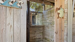 A wooden cabin with a shower area, a wooden door with a decorative plate, and a wooden wall with a wave design. - Close to beach, pier and restaurants (Surf City)