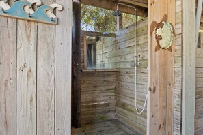 A wooden cabin with a shower area, a wooden door with a decorative plate, and a wooden wall with a wave design. - Close to beach, pier and restaurants (Surf City)