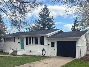A single-story house with a garage, a front porch, and a green door. - Quaint 4-bedroom house in peaceful Great Falls neighborhood perfect for families (Great Falls)