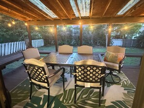 An outdoor patio with a table and chairs, string lights, and a view of the backyard. - Quaint 4-bedroom house in peaceful Great Falls neighborhood perfect for families (Great Falls)
