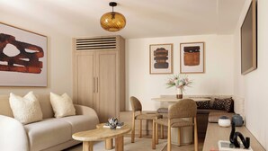 Una sala de estar moderna con un sofá, sillas, una mesa de centro, un comedor y obras de arte en las paredes.