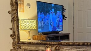 Une vieille valise sur laquelle est posée une télévision, avec un miroir et une bougie à proximité.