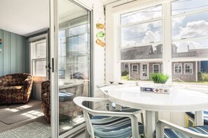A room with a round table, chairs, a sofa, and a sliding glass door leading to a garden. - Hybiscus - 2 BR - 2 Pets - BBQ -Parking - Walk to Beach & Hampton Strip (Hampton)