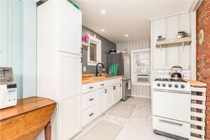 A compact kitchen with white cabinetry, a wooden countertop, a built-in oven, and a stove. - Hybiscus - 2 BR - 2 Pets - BBQ -Parking - Walk to Beach & Hampton Strip (Hampton)
