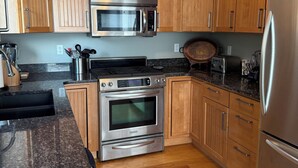 A kitchen with wooden cabinets, stainless steel appliances, and a granite countertop.