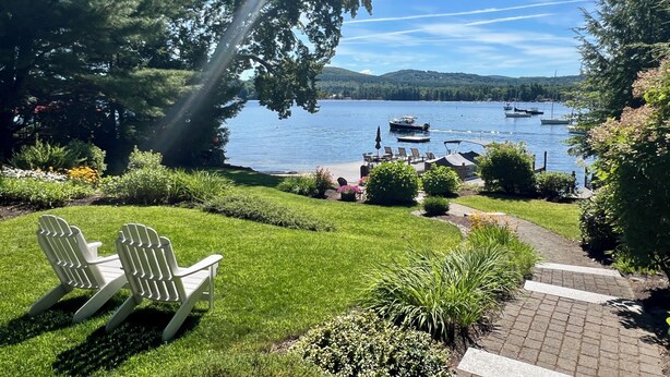 A lakeside view with boats, chairs, and a paved path.