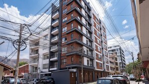 A multi-story residential building with balconies, a garage, and a clear sky. - Serene 2-bedroom apartment in charming Cusco near historic sites (Cusco)