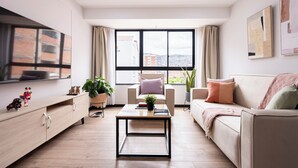 A modern living room with a sofa, armchair, coffee table, TV, and large windows with curtains. - Serene 2-bedroom apartment in charming Cusco near historic sites (Cusco)