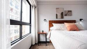 A hotel room with a bed, a small table, a window with curtains, and a wall-mounted artwork. - Serene 2-bedroom apartment in charming Cusco near historic sites (Cusco)