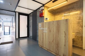 Un comptoir d’accueil avec un revêtement en bois, une enseigne indiquant « Résidence Sofia », et un détecteur d’incendie fixé au mur.