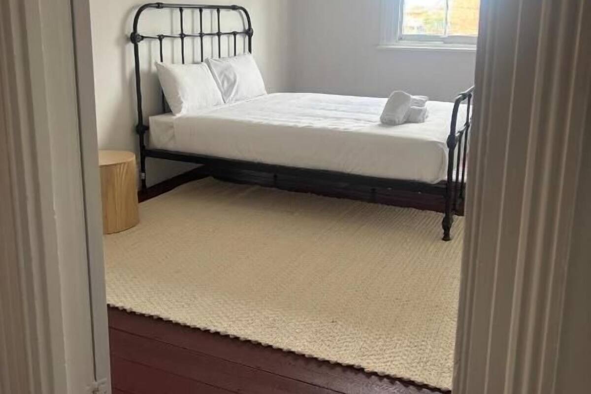 A bedroom with a bed, a window, and a door.
