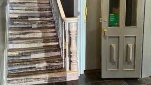 A staircase with patterned steps, a wooden door with glass panels, and a dark tiled floor.