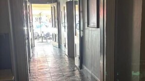A hallway with a stone floor, a green exit sign, and a hanging light fixture.