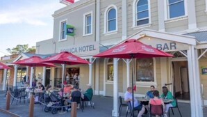 Un edifici amb un rètol que diu 'TAB' i 'SAULICA HOTEL BAR', amb seients a l'exterior i paraigües.