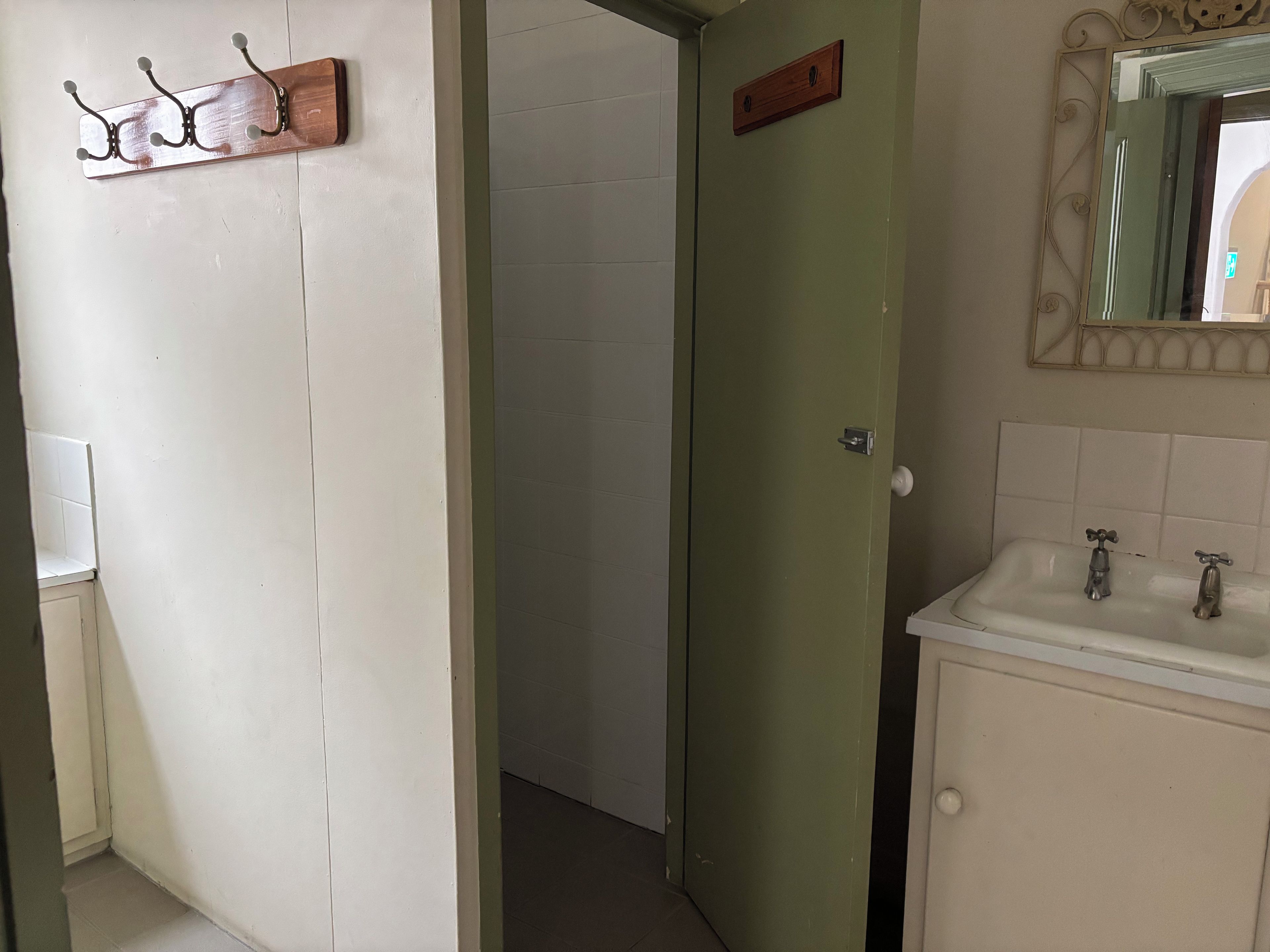 Un bagno con lavandino, specchio e porta che dà su un'altra stanza.
