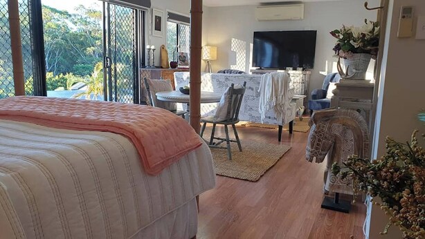 Un dormitorio con una cama, un escritorio, una silla y un televisor.